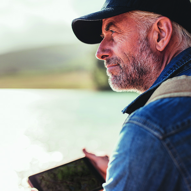 Mature man wearing cap sitting at a lake